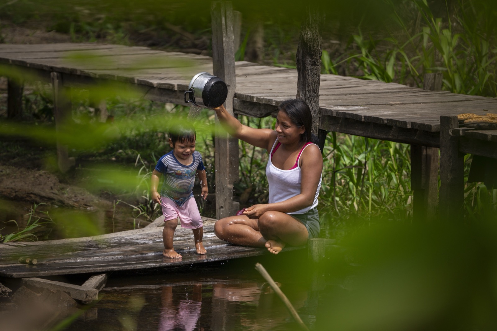 Madre bañando a niño en río