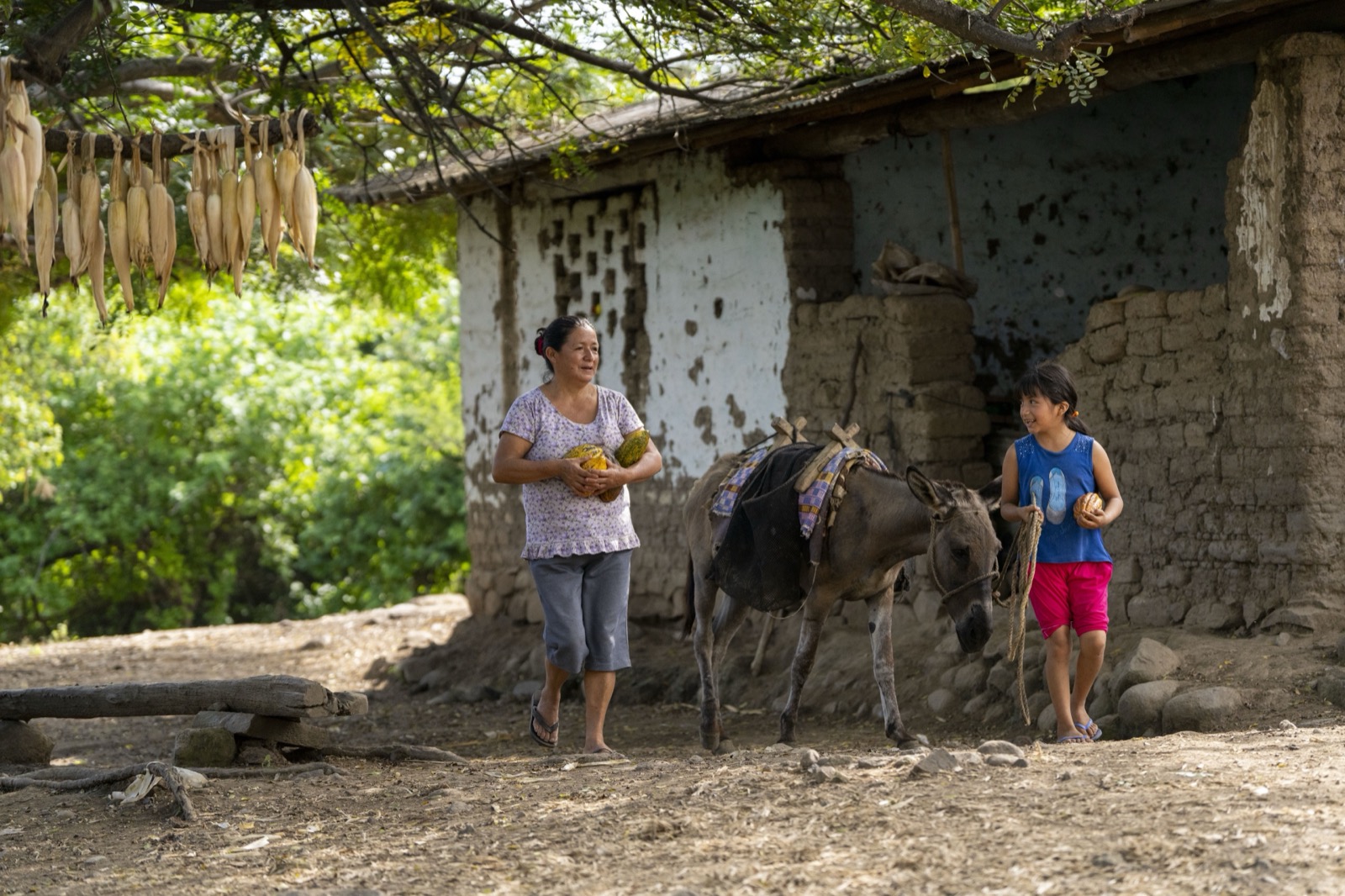 Mujer y niña con burro cerca de casa
