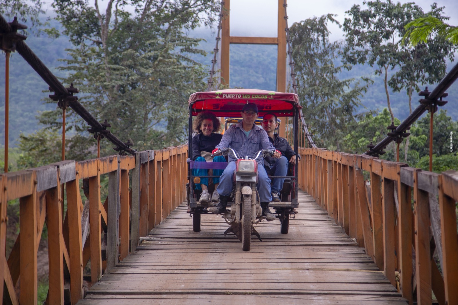 Personas en mototaxi cruzando puente