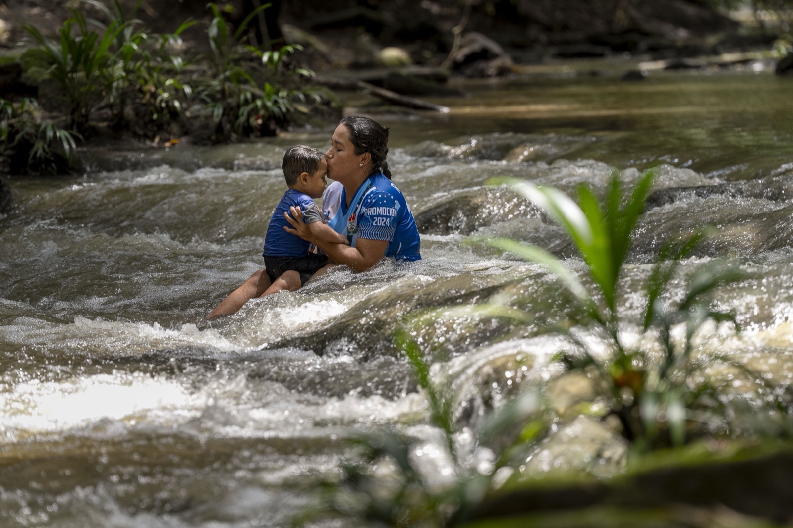 Madre besando bebé en río